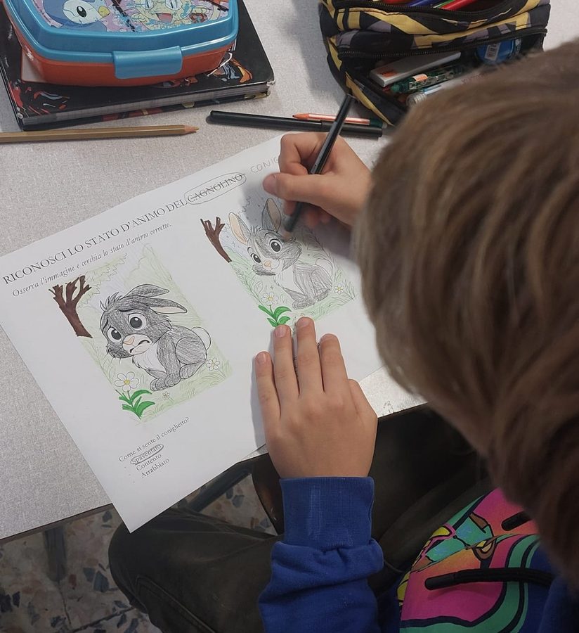 Un bambino colora una scheda per riconoscere lo stato d'animo del coniglietto